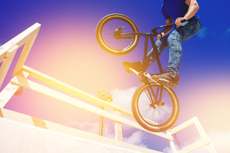 Guy is riding bmx bike, is preparing to jump on trampoline, ramp. Concept extreme teenagers.の写真素材