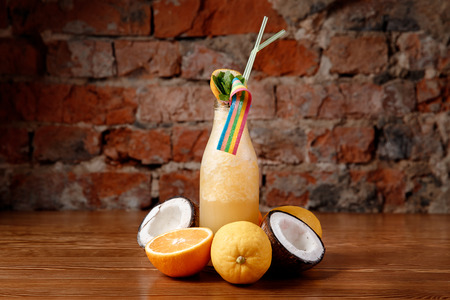 Smoothies of fresh berries yellow color. In background fresh lemons, oranges, coconut.の写真素材