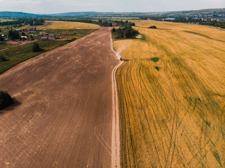 Tractor on farm field is carried by hay, view from above, aerial photographyの写真素材
