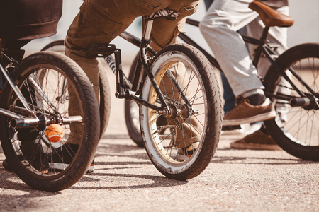 Teenagers stand in park for tricks with bicycles bmx, rear view, sunset light.の写真素材