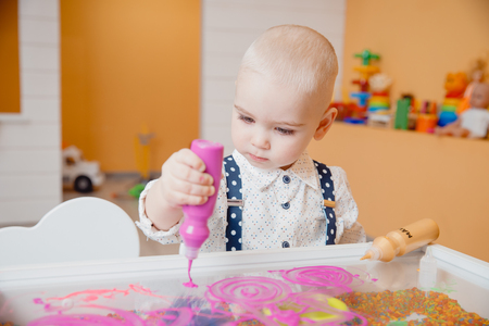 Child paints table with paint on transparent glass, concept development of kid motor skills of hands and art.の写真素材
