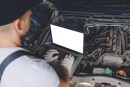 Professional car mechanic using electrnoic diagnostic equipment laptop in auto repair service.の写真素材