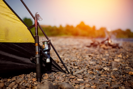 Fishing rod stands near tent. fisherman is preparing for river.の写真素材