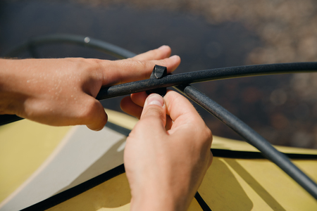 Man hands gather yellow tent, inserts into fastening loops.の写真素材