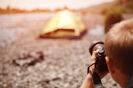 Photographer in journey selects angle and takes photo on professional camera, concept camping travelの写真素材