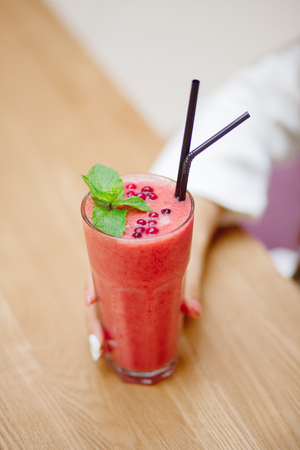 Young woman is holding useful smoothie from fresh berries and fruits in cafe.の写真素材