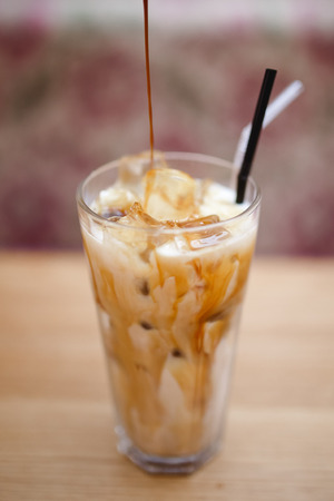 Barista prepares summer cold coffee with ice and milk in transparent glass.の写真素材