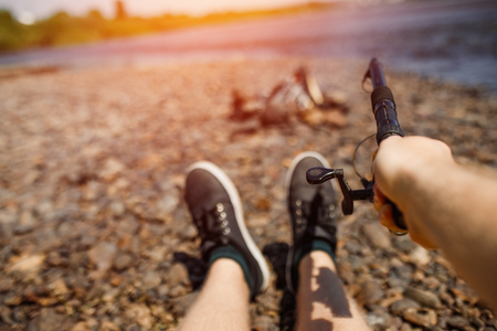 Man holds fishing rod from first person, river in background.の写真素材