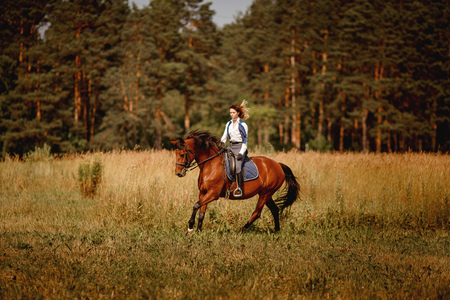 Young woman jockey gallop brown horse strolling across field. Concept rest for rich people.の写真素材
