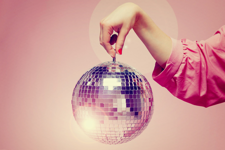 Mirror disco ball girl holding hand on pink background. Concept party, holiday. Copy spaceの写真素材