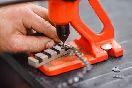 Woodcutter man repairs chainsaw, sharpens chain in forestの写真素材