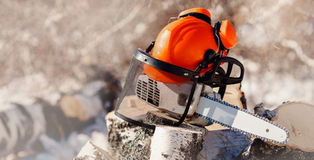 Chainsaw and protective helmet with headphones lie on sawn wood on sawmill.の写真素材