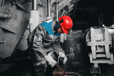 Young miner man underground in mine for coal mining overalls is busy with work, repairing against backdrop of equipment. Portrait.の写真素材