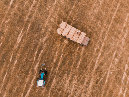 Aerial view drone of harvest field with tractor moving hay baleの写真素材