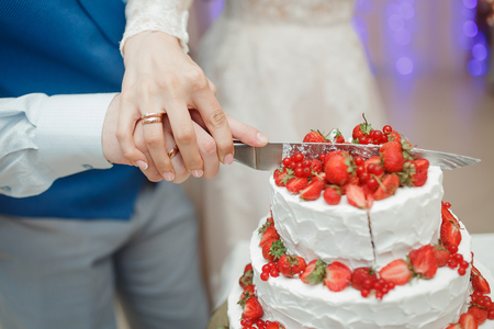 Bride and groom cutting wedding cake with knifeの写真素材