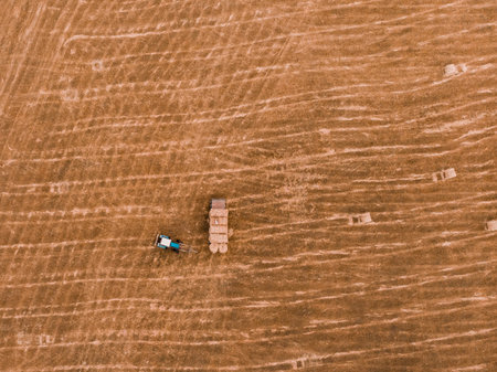Aerial view drone of harvest field with tractor moving hay bale