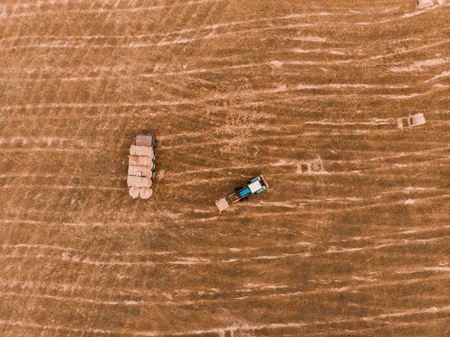 Aerial view drone of harvest field with tractor moving hay baleの写真素材
