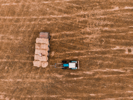 Aerial view drone of harvest field with tractor moving hay baleの写真素材