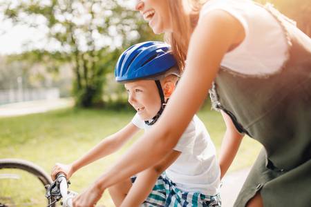 Sister and little brother learning to ride bicycle park having fun togetherの写真素材