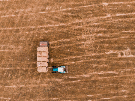 Aerial view drone of harvest field with tractor moving hay baleの写真素材