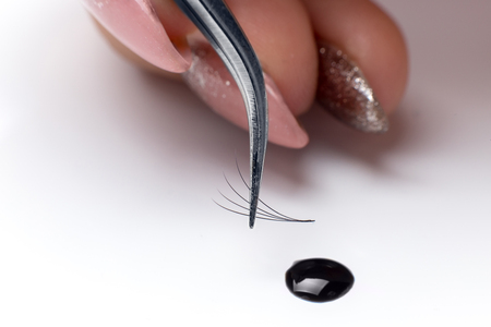 Closeup eyelash extension tweezers tools on white background. Artificial lashes 4D drop of glue.の写真素材