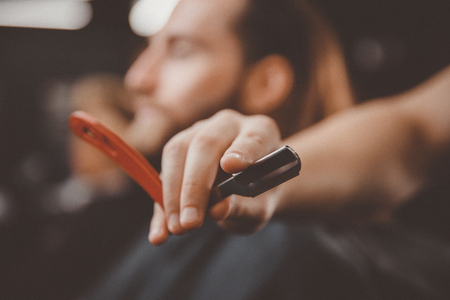 Razor in foreground hands of barber. Concept barbershop for men.の写真素材
