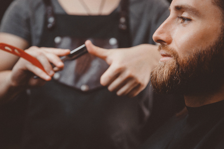 Barber process shaving razor bearded hipster man in barbershop.の写真素材