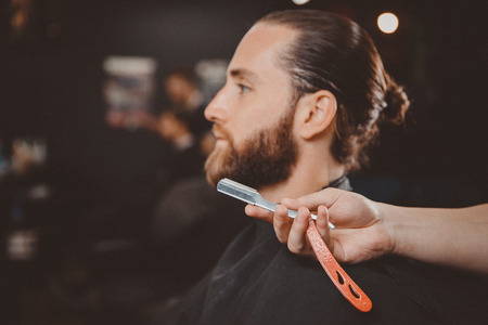 Razor in foreground hands of barber. Concept barbershop for men.の写真素材