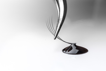 Master of artificial eyelashes forms bundle in drop glue with tweezers 4D.の写真素材
