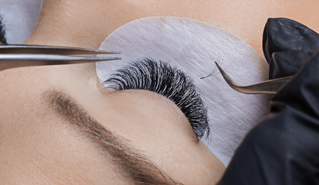 Eyelash extension procedure. Woman master making long lashの写真素材
