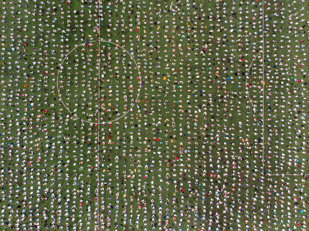 Top view drone of crowd of people on sports stadium football green lawn.