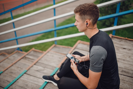 Fitness runner man before training puts on headphones listen music from telephoning. Concept lifestyle workout.の写真素材