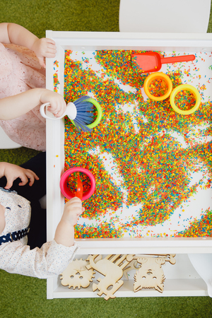 Top view, children play table in colored sand with scoop and bucketの写真素材