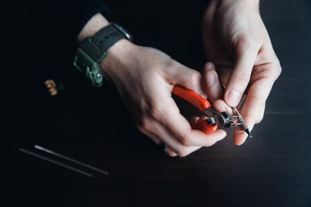 male master installs a coyle. Spiral for electronic evaporator and cigarette. Vape, vaping. Pliers, wire, fichral, coil, screwdriverの写真素材