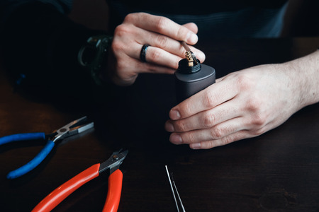 male master installs a coyle. Spiral for electronic evaporator and cigarette. Vape, vaping. Pliers, wire, fichral, coil, screwdriverの写真素材