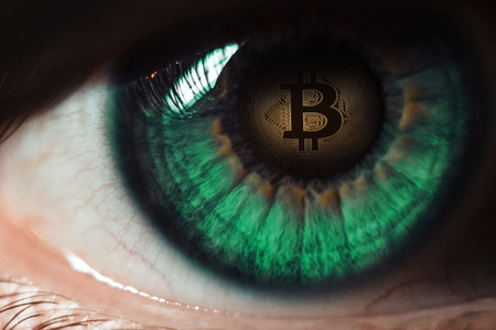 Bitcoin. Eye of a person with the bitcoin coin logo in the pupilの写真素材