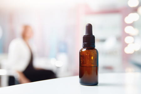 Closeup of oil for hair and skin care in bottle with dispenser, background client spa salon is sitting chair.の写真素材