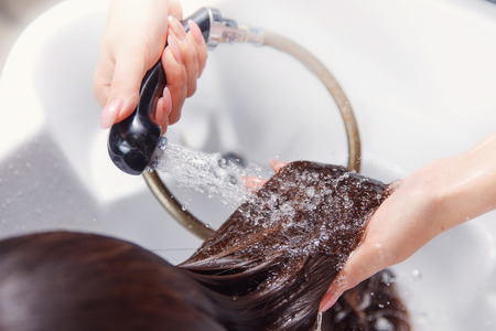 Master hairdresser woman shampooing in white sink spa salon hair.の写真素材