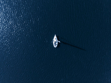 Alone white sail in sea blue on bright Sunny day casts shadow from bird eye view