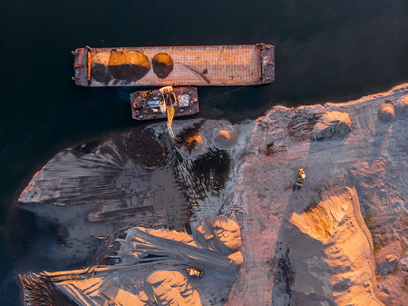 Crane is loading sand and gravel onto barge ship for river transport. Aerial drone