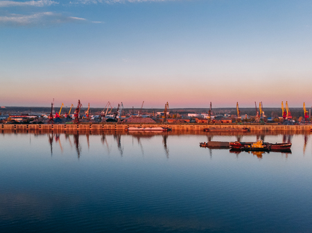 Port river cranes loading ships on barges delivery, sunset. Aerial droneの写真素材