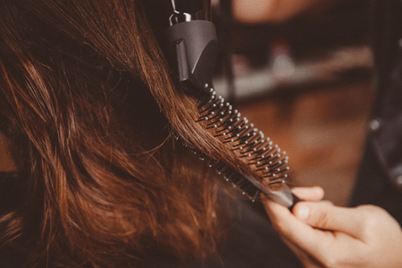 Barber makes hair styling to man with hairdryer and comb.の写真素材
