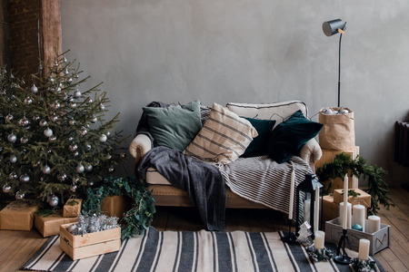 New Year interior apartment, sofa, blanket, pillows, gray scale tree gifts. loft styleの写真素材