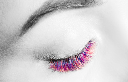 Beautiful woman on color eyelash extension procedure in spa salon. Concept fashion blackの写真素材
