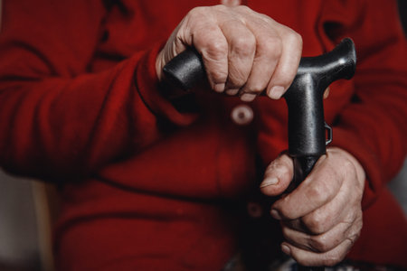 Hands of old woman holding cane, skin wrinkled.の写真素材