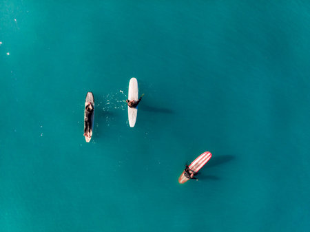 Three surfers in black wetsuits open sea, turquoise water, foam, warm Sunny day. Close up. Top view...
