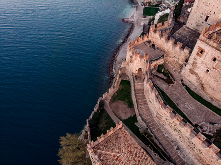 Lake Lago Garda - view of Malcesine village. Old castle on rock Italy. Aerial photo sunsetの写真素材