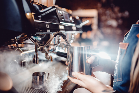 Process of preparing milk foam for cappuccino, heating and whipping. Barista controls temperature by holding pitcher in his hands.の写真素材