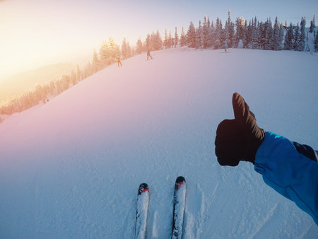 Man athlete shows up thumb Class on background of snow in skis. Action camera is fixed head helmet.の写真素材