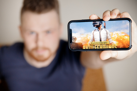Moscow, Russia - January 1, 2019 : Man holding smartphone with Player Unknown Battleground PUBG online shooting gaming.のeditorial素材